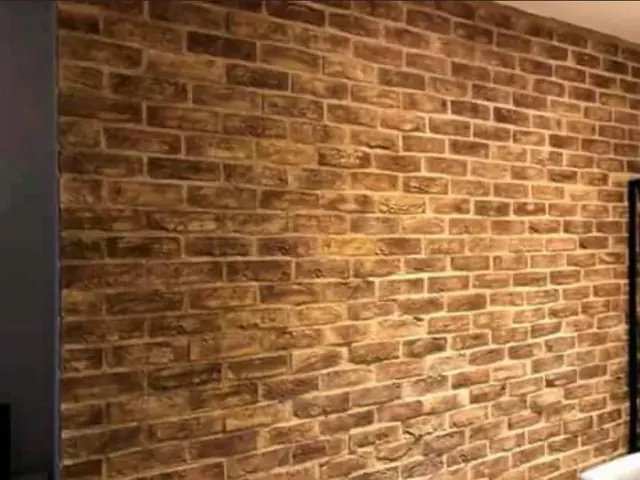 Exposed red brick feature wall inside a finished room, with pale mortar and dark feature bricks.