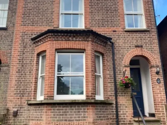 Repointed Victorian brick house with restored bay window and arched entrance.