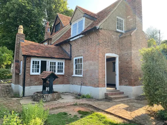 Rear of a restored period brick house with completed brickwork and landscaping underway.