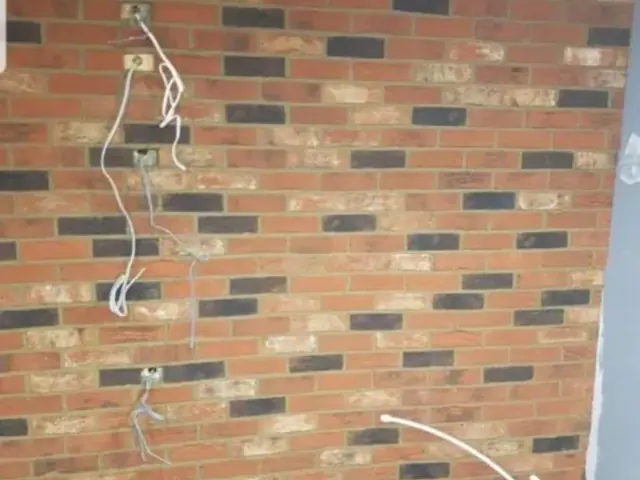 Interior brick feature wall during installation with electrical cables exposed.