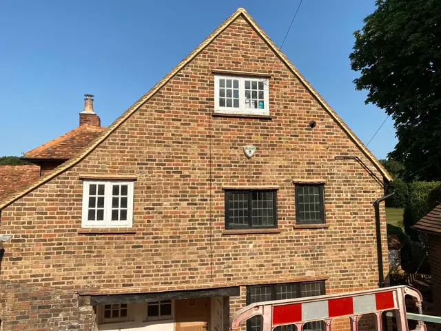 Restored rear gable of a period brick house with white timber windows.
