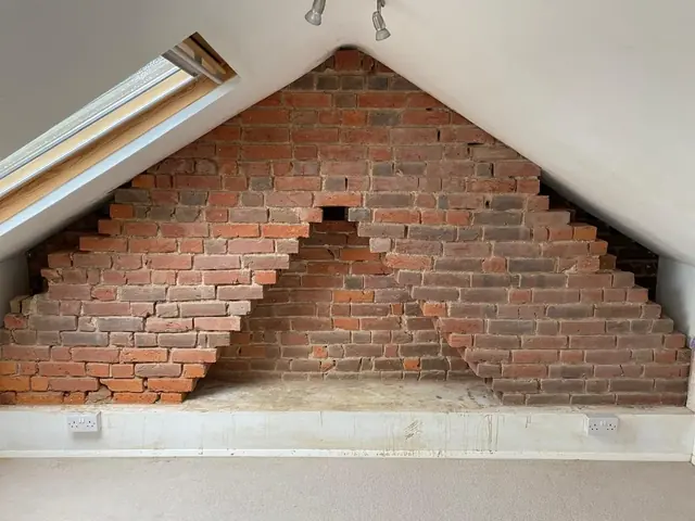 Exposed brick gable feature wall inside a loft room during restoration.
