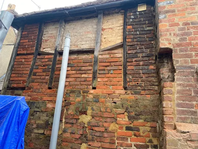 Historic timber framed wall with damaged brick infill before restoration.