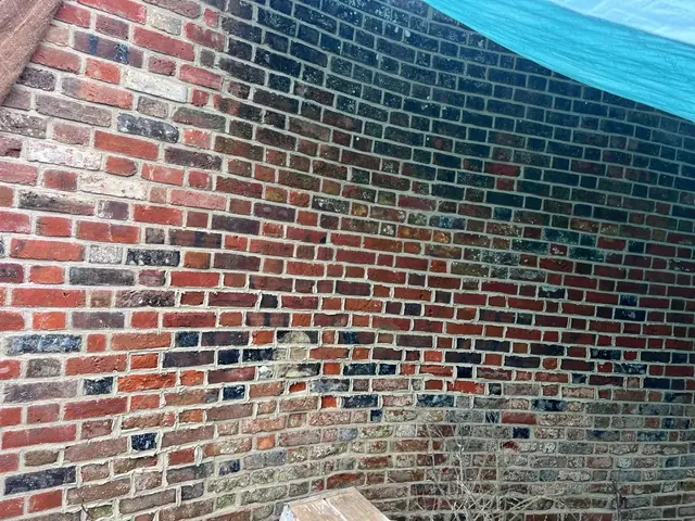 Close view of a mixed red brick wall with renewed pale mortar joints.