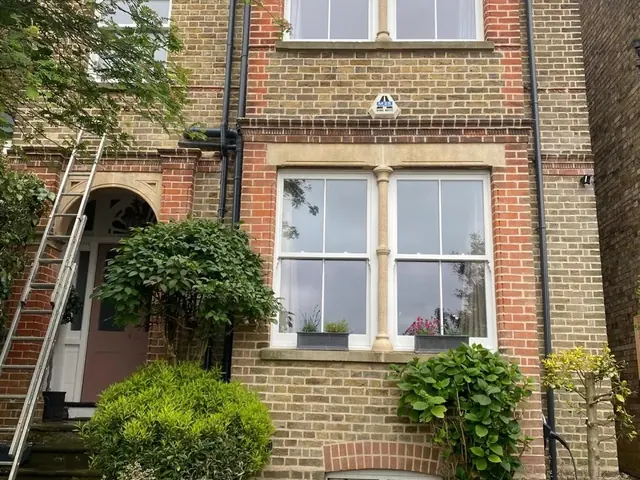 Tall Victorian brick townhouse with bay windows before exterior work.
