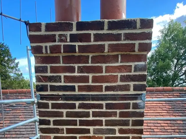 Repointed red brick chimney stack viewed from scaffold.