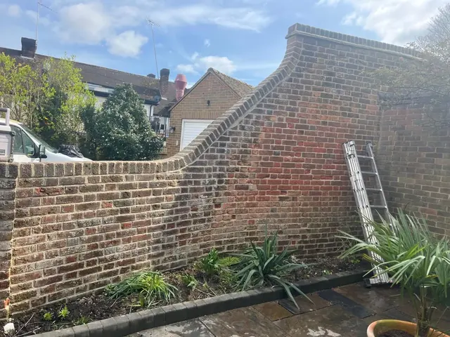 Curved brick garden wall with a stepped top before repair.