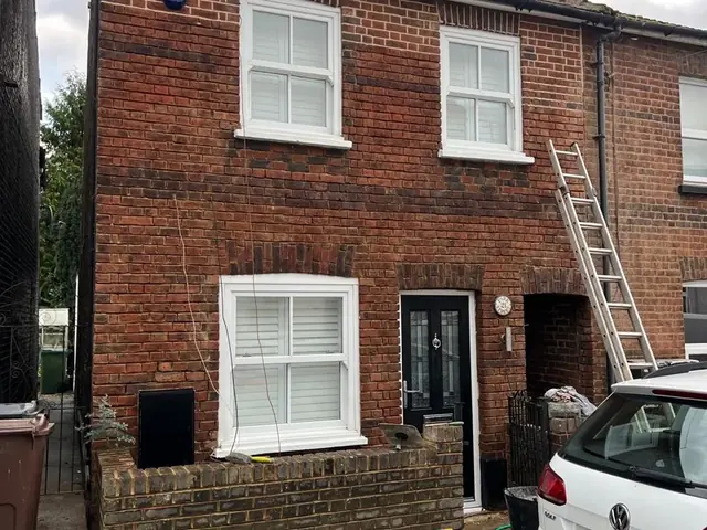 Brick terraced house during repointing with a ladder at the front.