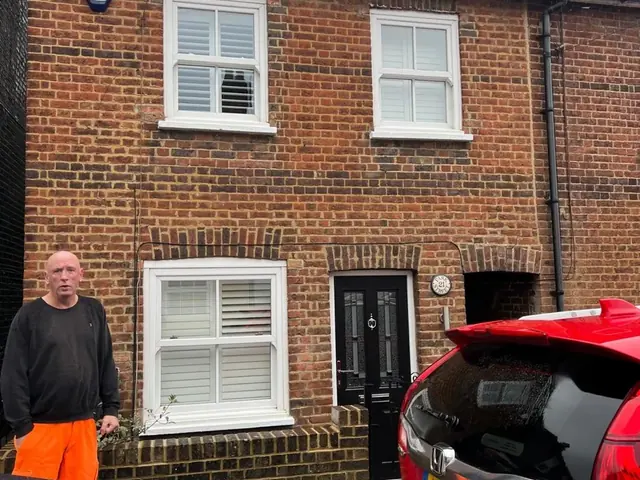 Brick terraced house during work with a contractor standing outside.