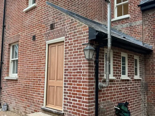 Rear elevation of a period lodge with renewed red brickwork and a new timber door.