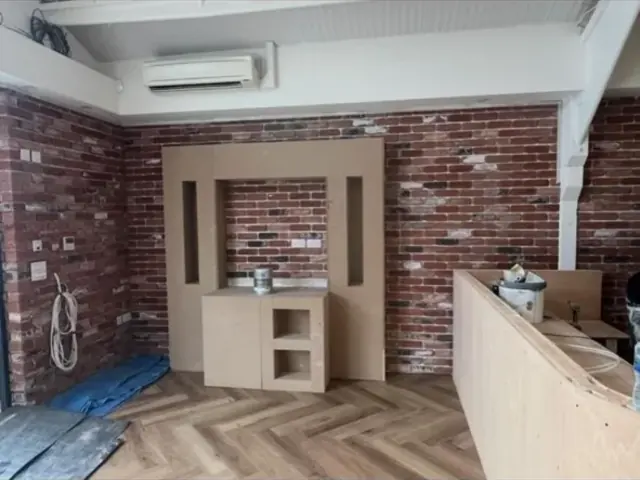 Interior brick feature wall and fitted media unit during refurbishment.