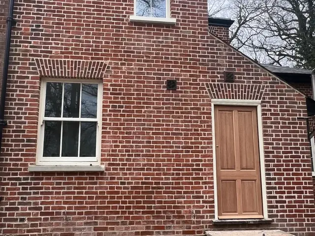 Rear red brick elevation after repointing, with a new timber door and steps.