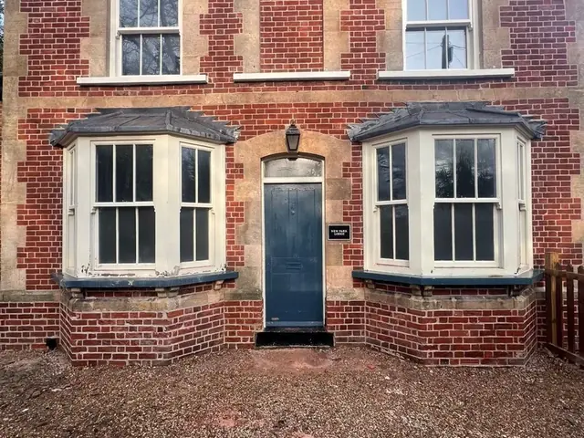 Front of a period lodge after brick restoration, with bay windows and a central door.