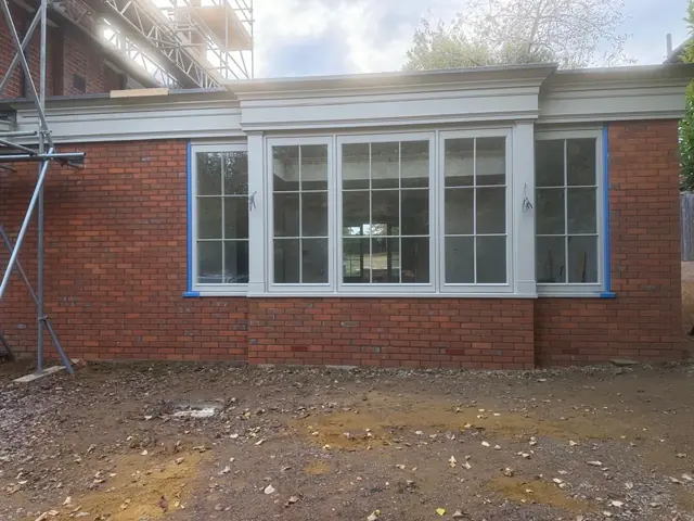 Red brick extension with large multi pane windows before final paint and clean down.