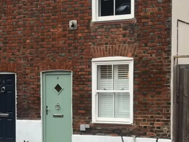 Weathered red brick cottage facade before repointing.