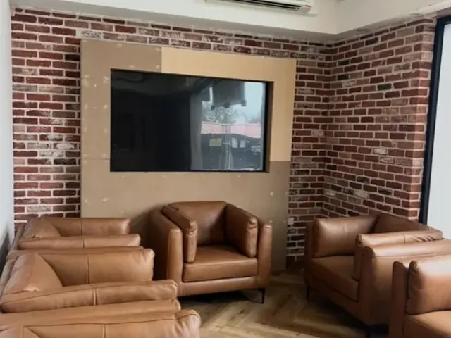 Finished seating room with exposed brick walls and brown leather chairs.