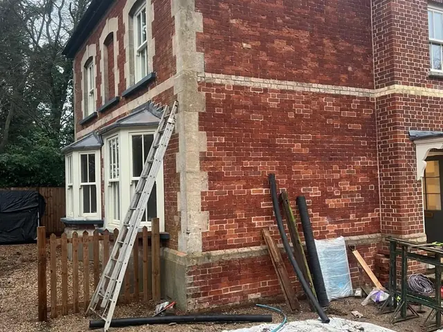Side elevation of a period lodge during ground works and brick restoration.