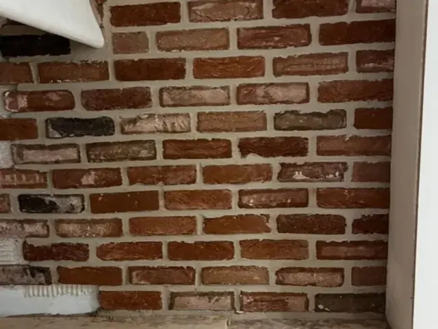 Interior exposed brick feature wall beneath a sloping ceiling.