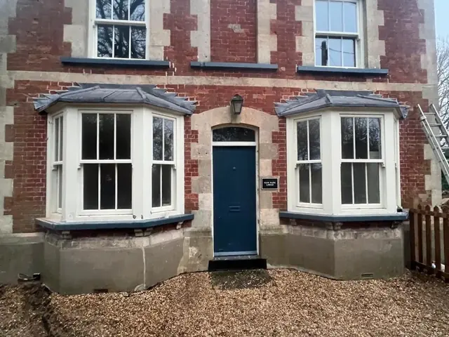 Front elevation of a period lodge after masonry restoration and bay window repairs.