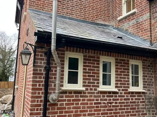 Restored single storey brick wing with three white timber windows.