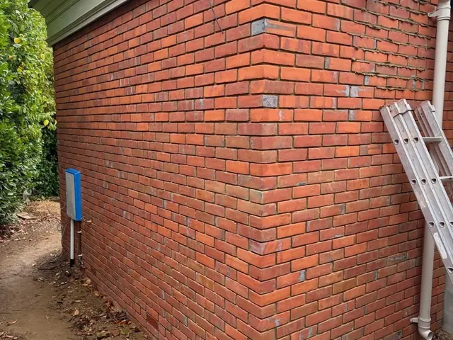 Corner of a completed red brick extension showing neat new masonry and vents.