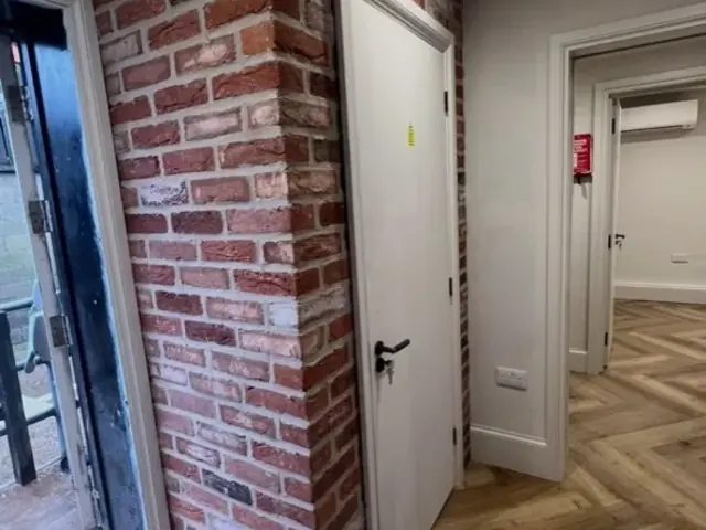 Finished exposed brick column beside an internal doorway and herringbone floor.