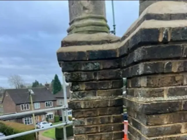 Weathered twin chimney stacks before pointing repairs, viewed from scaffold.