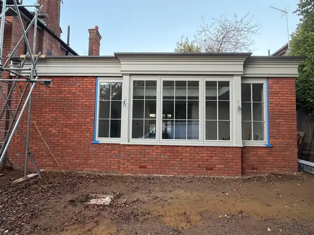 Completed red brick extension facade with large multi pane windows.