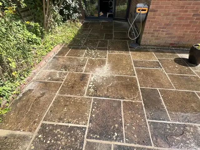 Cleaned stone patio leading to black glazed garden doors.
