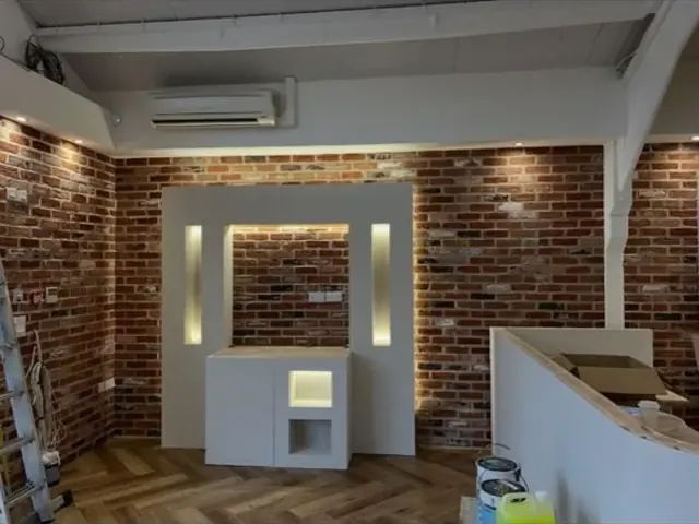 Interior exposed brick media wall with illuminated display niches during fit out.