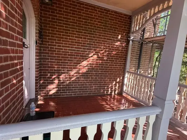 Completed covered brick porch with a painted balustrade and tiled floor.
